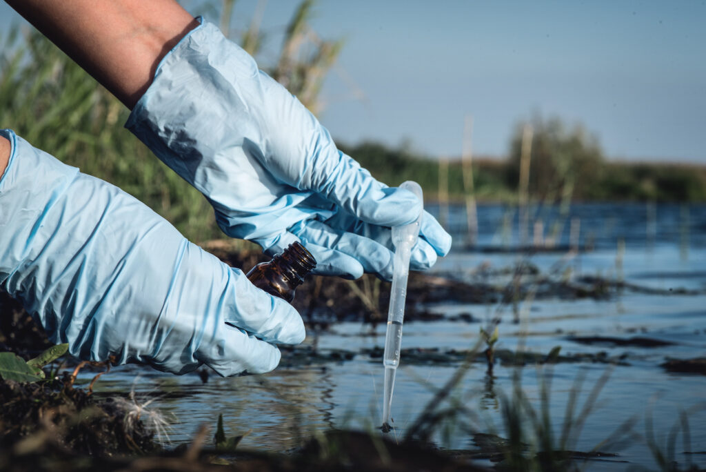 Prélèvement d’eau dans un cours d’eau pollué pour analyser la présence de matières en suspension.