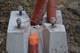 Détail d’un massif béton pour candelabre avec ancrage par boulons, gaines électriques et mise à la terre
